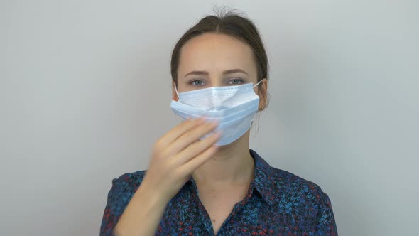 Woman in protective medical mask using hand sanitiser to reduce infection spreading risk. Quarantine