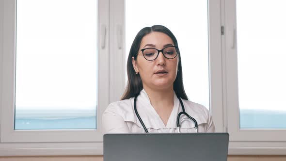 Woman Consults Patient Via Videocall on Laptop in Office