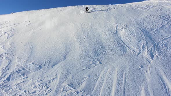 Extreme Skier Slides Down a Steep Snow Slope in the Mountains Between Rocks Aerial View