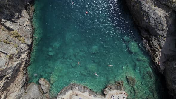 People jump into turquoise sea water. Drone footage of the Kalupso wild beach