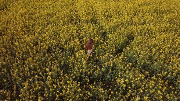 Girl on the Field Among Canola Flowers