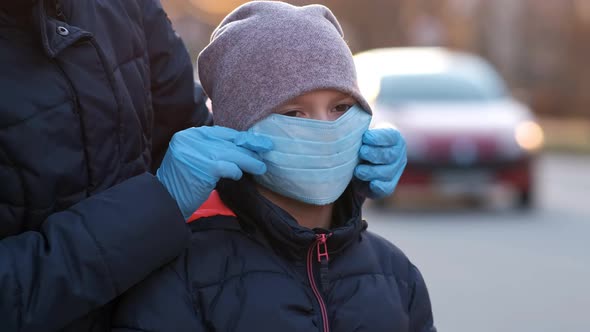 Mother adjusts her daughter's medical mask on the street of a European city .