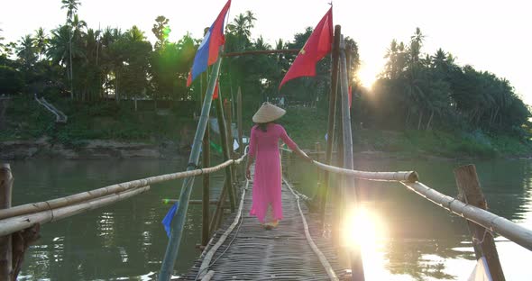 Vietnamese Girl In Traditional Dress Walking On Bamboo Bridge Cross River