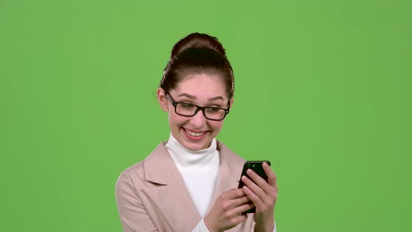 Business Lady Looks at Photos on Her Smartphone. Green Screen. Slow Motion