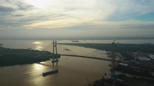 drone view of Ship moving towards large modern suspension bridge in early morning light. drone moves