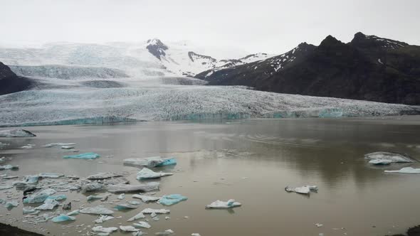 Glacier in Iceland with water, mountains and blue ice with drone video moving sideways.