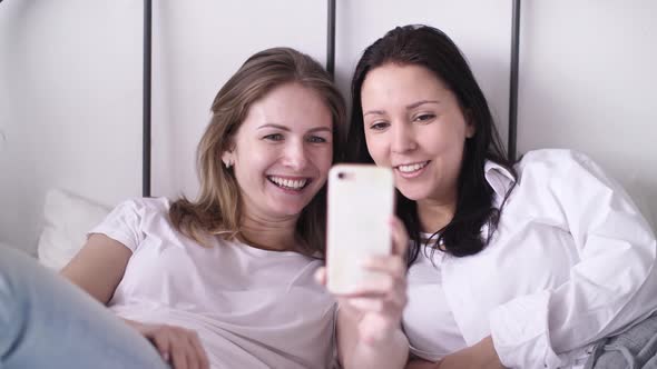 Two Young Women Taking Selfie Portrait on Phone Female Showing Positive Face Emotions Laughing 