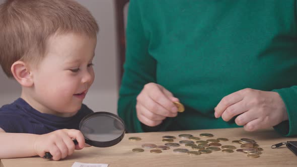 Portrait Baby Boy Kid Looking at Money Coins with Magnifying Glass Hands Helping