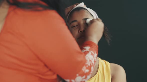 Close up of make up artist cleaning young woman's face and preparing it for make up