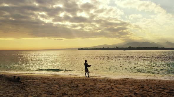 One man fishing on idyllic shore beach journey by transparent ocean and white sand background of Lom