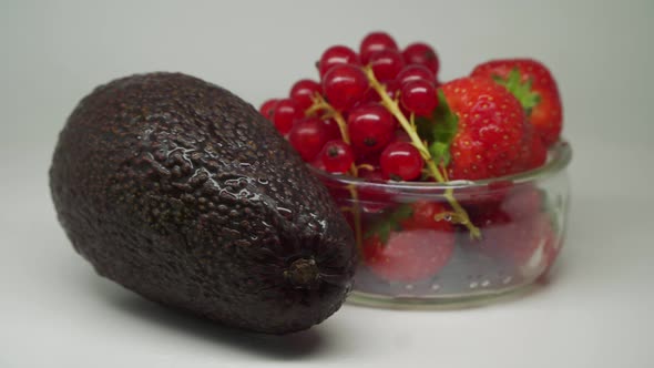 Delicious Ripe Fruits -  Cherries, and Strawberry Inside The Small Transparent Bowl And Avocado Rota