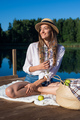 Beautiful young woman wearing blue shorts, shirt and hat enjoys her morning picnic on a wooden pier - PhotoDune Item for Sale
