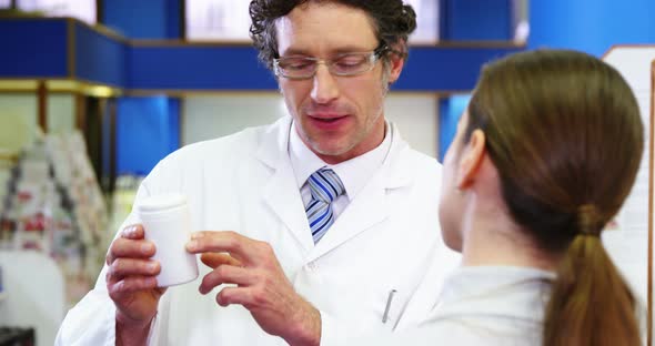 Pharmacist assisting the bottle of drug to customer