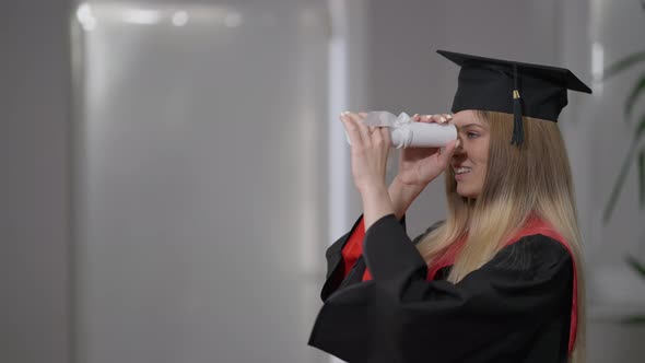 Side View Cheerful Caucasian Grad Woman Using Rolled Diploma As Spyglass Smiling