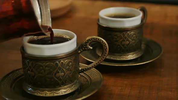 Two Cups of Black Coffee Being Poured From a Turk