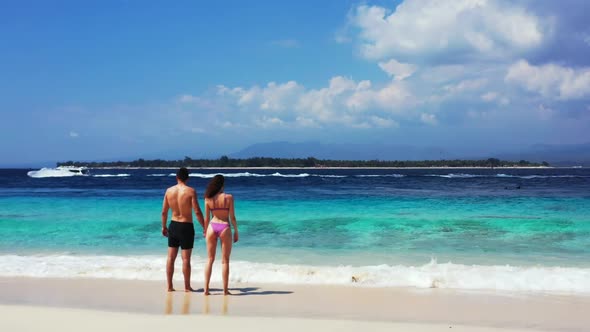 Two lovers in love on relaxing bay beach vacation by aqua blue lagoon with white sand background of 