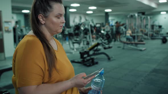 Caucasian woman with overweight using mobile phone at the gym. Shot with RED helium camera in 4K.