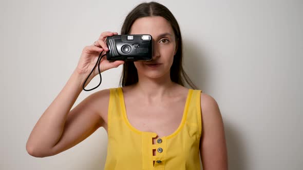 Girl Photographer in a Yellow T-shirt Takes a Soap Dish on an Old Plastic Camera