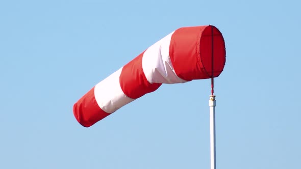 Closeup on a Red and White Windsock in the Gusty Wind - the Clear Blue Sky in the Background