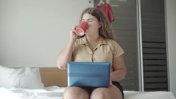 Confident Young Plus-size Woman Checking E-mail in the Morning and Drinking Coffee. Portrait of