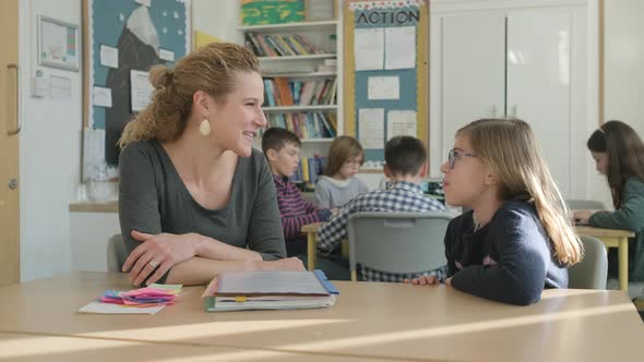 Girl speaking with teacher in classroom