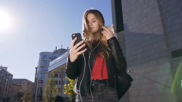 Attractive Young Woman with Long Hair in Headphones Using Smartphone 