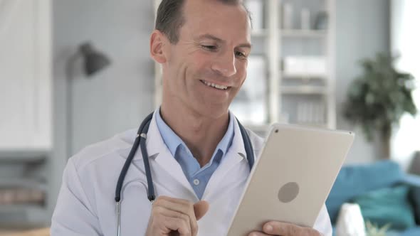 Senior Doctor Discussing with Patient Via Video Chat on Tablet