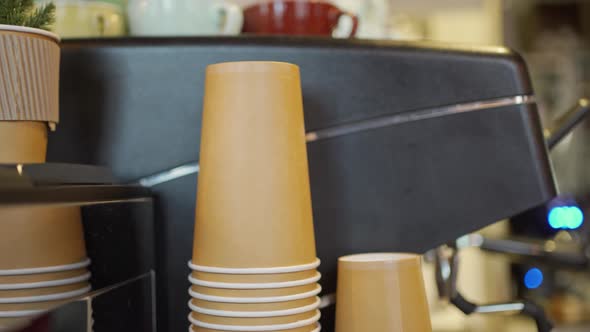 Brown Cardboard Coffee Cups Stacked in Each Other Next to a Professional Coffee Machine in the