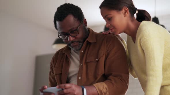 Cheerful daughter and father looking at phone