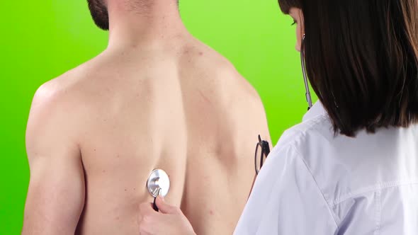 Woman Doctor Is Listening Lungs Man Stethoscope. Green Screen