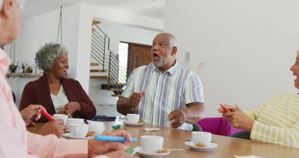 Happy senior diverse people drinking tea and playing bingo at retirement home