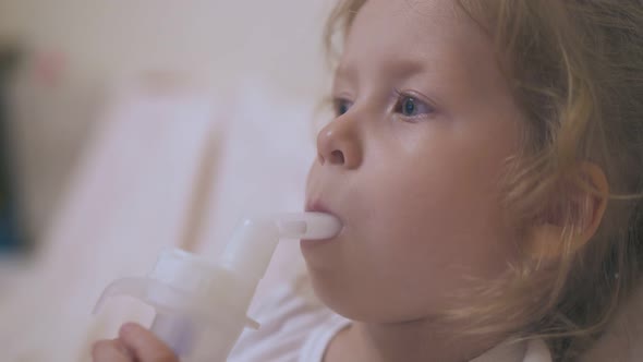 Little Girl Breathes with Inhaler Lying in Comfortable Bed