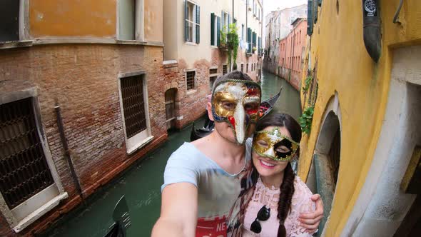 Couple wearing venetian masks at a small canal in Venice city, Italy, Europe