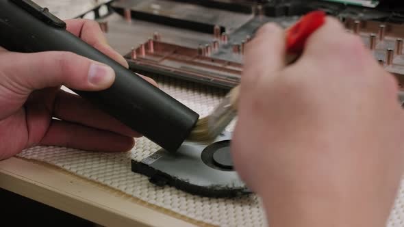 Closeup of a Repairman Cleaning a Computer Fan with a Brush in the Workshop