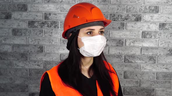 Portrait of Young Woman in Medical Mask on Her Face on Background of Gray Brick Wall