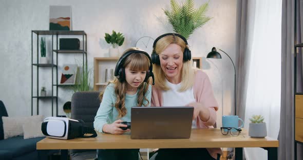 Girl Making Upset Face when Playing Videogames Together with Her Attractive Happy Cheerful Mother