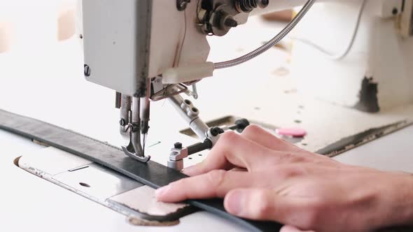 The Craftsman Stitches a Men's Leather Belt on a Sewing Machine