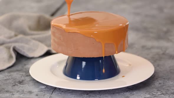 Pastry Chef Decorating Chocolate Mousse Cake with Caramel Mirror Glaze.