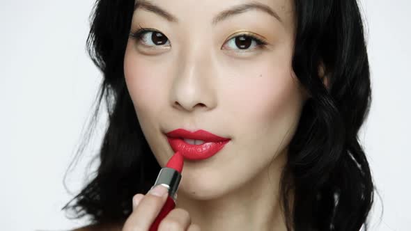 Young woman applying red lipstick