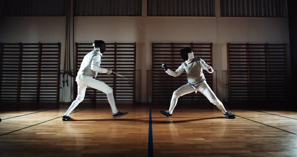 Two Men In Fencing Gear Duelling With Foils