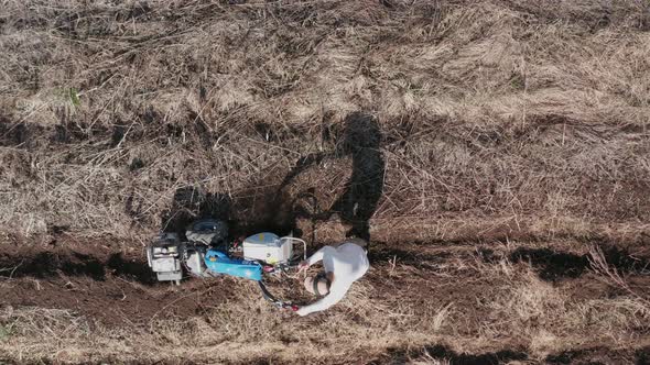 AERIAL - Man working a field with a rototiller, agriculture, wide shot zoom out