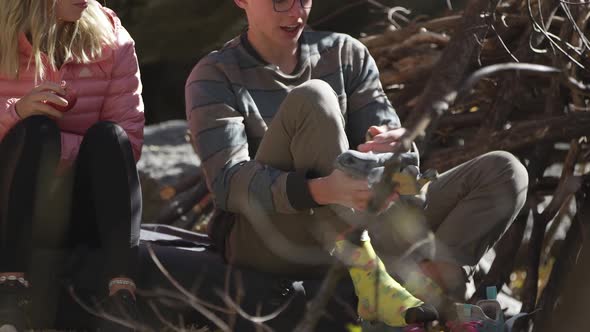 Young man taking of shoes and socks to put on rock climbing shoes