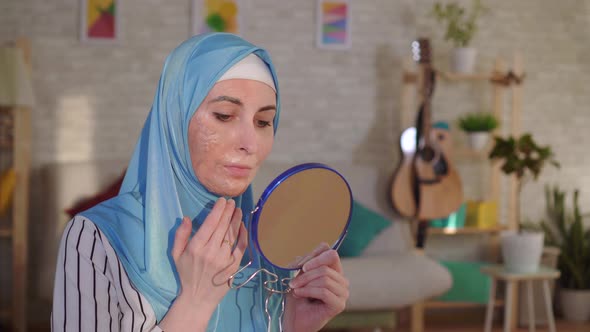 Muslim Woman in a Hijab Looks in the Mirror at Her Scar From a Burn on Her Face and Cries