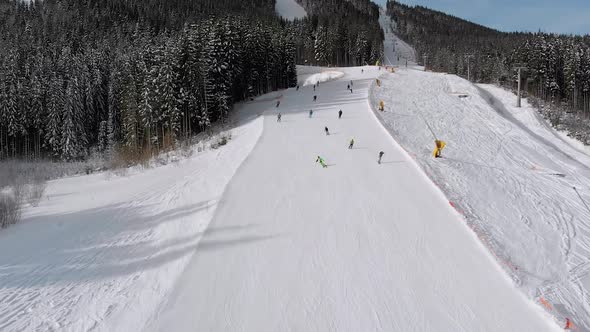 Aerial View Lot of Skiers Go Down the Ski Slopes. Drone Flies Low Next To Skiers