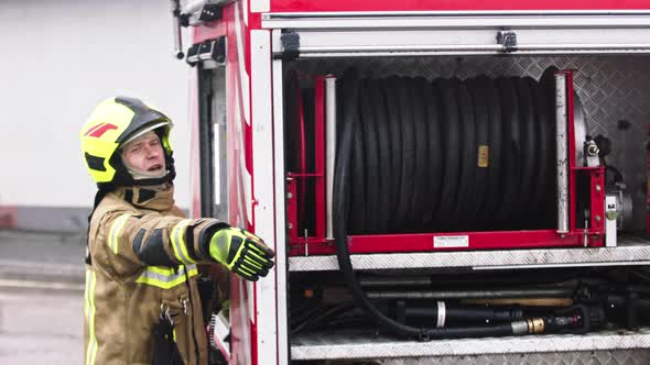 Fireman Standing in Front of the Fire Truck Ready To Unroll the Hose