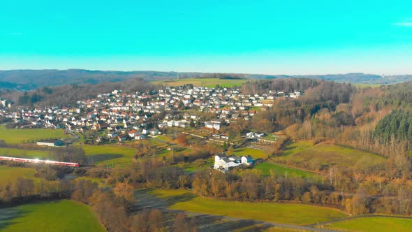 drone flight over a small town with a passenger train passing by