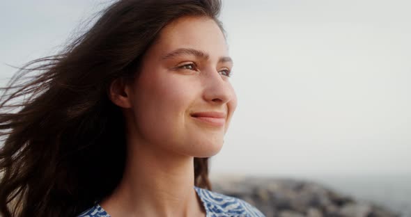 A Beautiful Young Woman Smiles Looking Into Distance the Wind Develops Her Hair