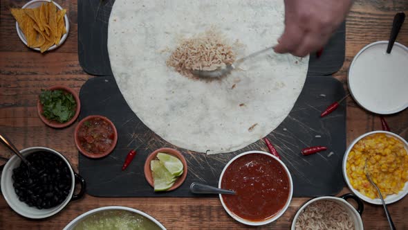 Overhead View of a Hand Preparing Tortilla By Adding Various Fresh Healthy Ingredients