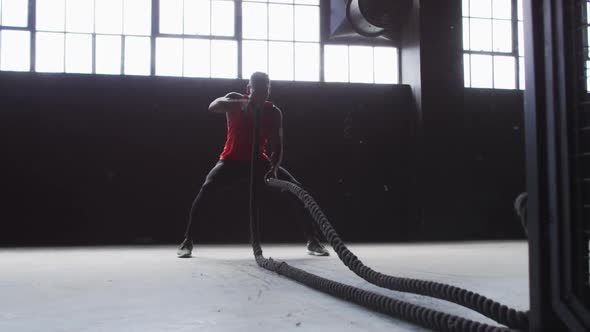 African american man exercising battling ropes in an empty urban building