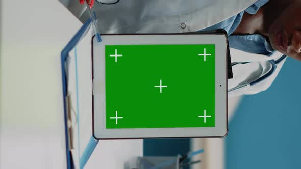 Vertical Video Close Up of Doctor Vertically Holding Tablet with Green Screen